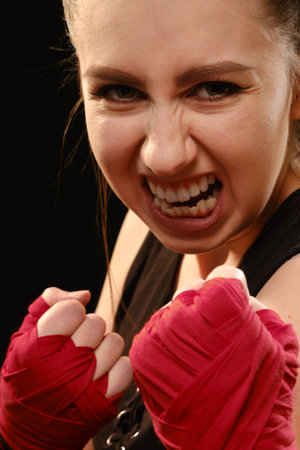Muay Thai female boxer in attack pose. Fitness young woman boxing training on black backgroundの写真素材