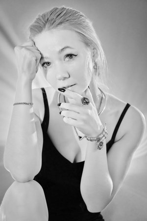 Beauty portrait of a sad woman in black dress with bare shoulders, blond hair looking at camera monochromeの写真素材