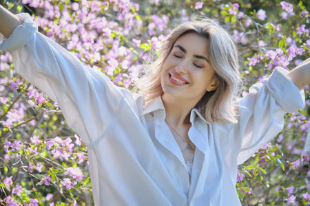 Happy woman smiling near magnolia tree with blossoming flowers