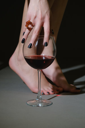 female hand with amber ring touch wineglass on gray background closeup viewの写真素材
