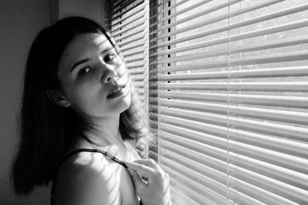 sensual aroused girl in lingerie near window in sunlight with blinds, monochromeの写真素材