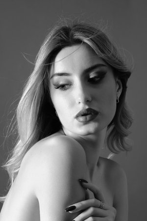 sensual young blond woman with bare shoulders on gray background monochromeの写真素材