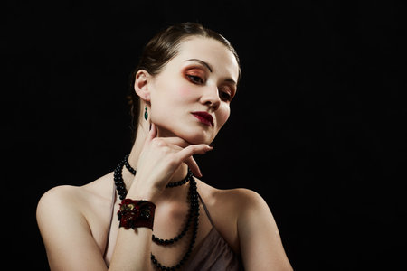 Young sad woman posing sensually holding head up on black background, closed eyesの写真素材