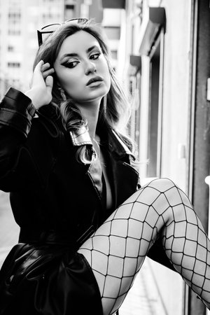 autumn fashion trends. Red hair woman in black leather coat posing in the street. monochromeの写真素材