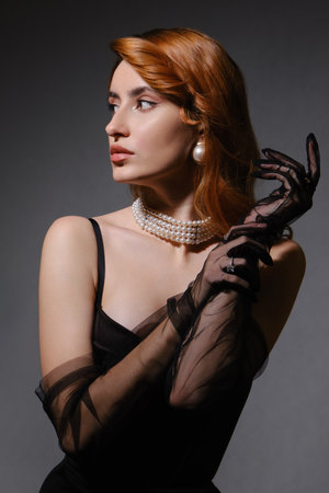 Fashionable photo of elegant girl with nice wavy red hairstyle, bare shoulders. Serious sad woman on gray background with copy spaceの写真素材