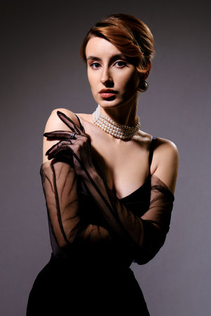 Beautiful young woman in black dress and pearl necklace. Studio shot.の写真素材