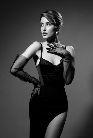 Fashionable photo of elegant girl with nice hairstyle, bare shoulders. Serious sad woman on gray background with copy space, monochromeの写真素材