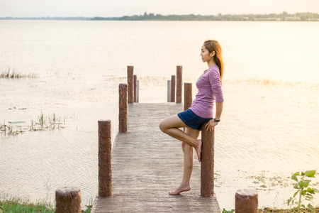 young girl is sitting on a wooden bridgeの写真素材