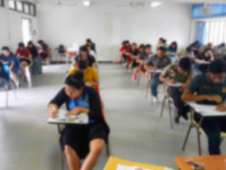 Blur school background university students writing answer doing exam in classroomの写真素材