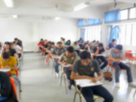 Blur school background university students writing answer doing exam in classroomの写真素材