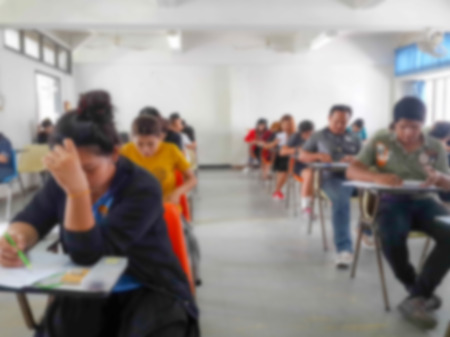 Blur school background university students writing answer doing exam in classroomの写真素材