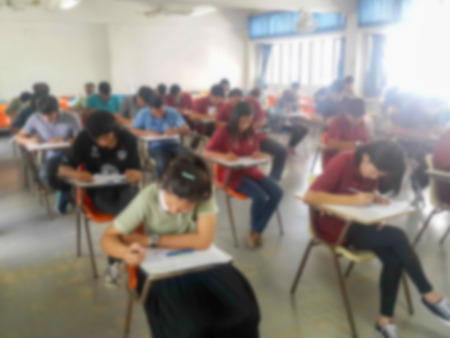 Blur school or university students writing answer doing exam in classroomの写真素材