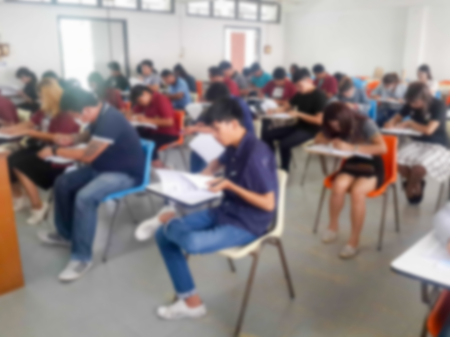 Blur school or university students writing answer doing exam in classroomの写真素材