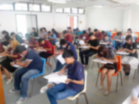 Blur school or university students writing answer doing exam in classroomの写真素材