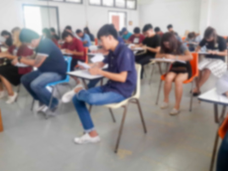 Blur school or university students writing answer doing exam in classroomの写真素材