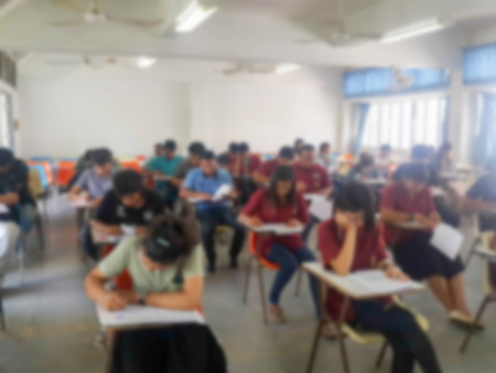 Blur school or university students writing answer doing exam in classroomの写真素材