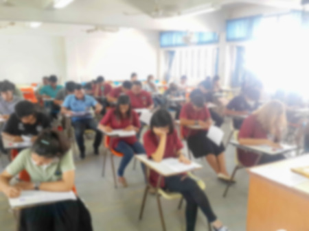 Blur school or university students writing answer doing exam in classroomの写真素材