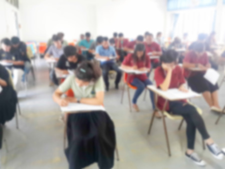 Blur school or university students writing answer doing exam in classroomの写真素材