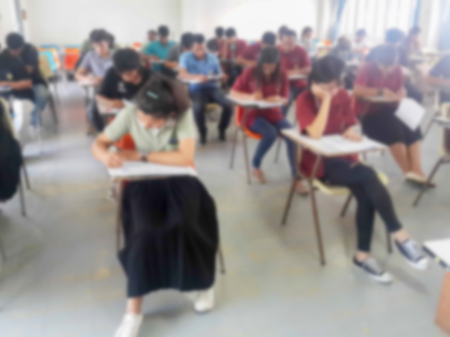 Blur school or university students writing answer doing exam in classroomの写真素材