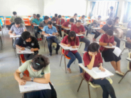 Blur school or university students writing answer doing exam in classroomの写真素材