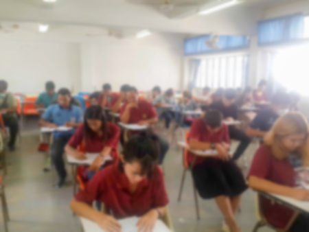 Blur school or university students writing answer doing exam in classroomの写真素材