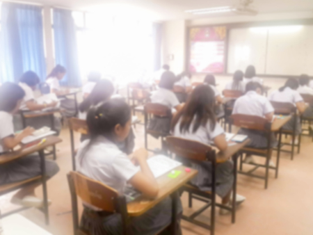 Blur school or university students writing answer doing exam in classroom.の写真素材