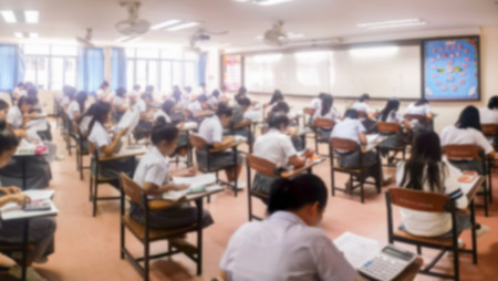 Blur school or university students writing answer doing exam in classroom.の写真素材
