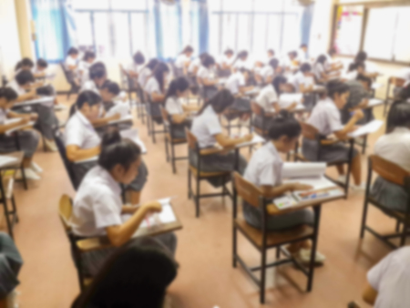 Blur school or university students writing answer doing exam in classroom.の写真素材