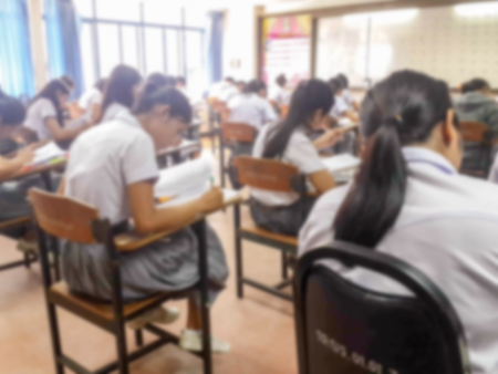Blur school or university students writing answer doing exam in classroom.の写真素材