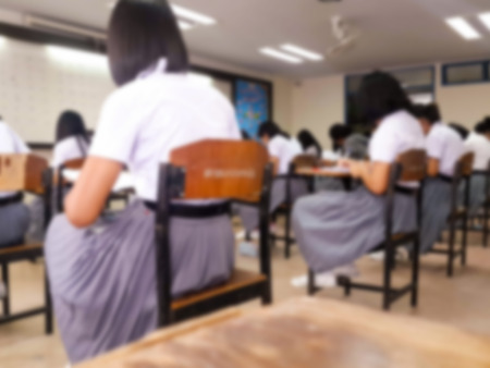 Blur school or university students writing answer doing exam in classroom.の写真素材