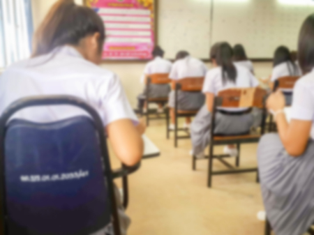 Blur school or university students writing answer doing exam in classroom.の写真素材