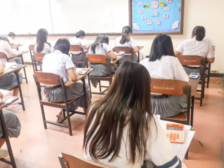 Blur school or university students writing answer doing exam in classroom.の写真素材