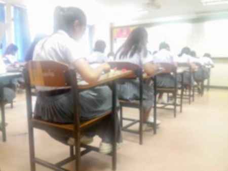 Blur school or university students writing answer doing exam in classroom.の写真素材