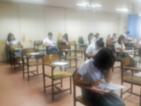 Blur background university students writing answer doing exam in classroom, view from back of the classの写真素材