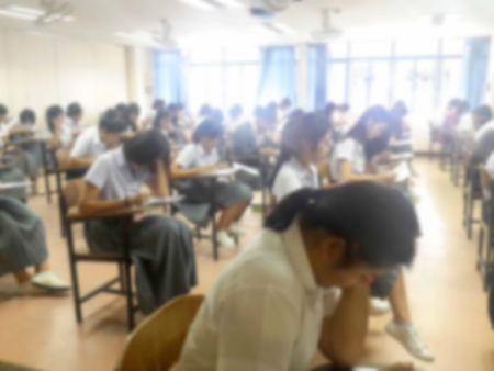 Blur background university students writing answer doing exam in classroom, view from back of the classの写真素材