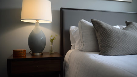 interior of a hotel room with a bed and a table lampの素材
