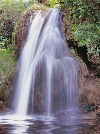 Small mountain waterfall with reflectionの写真素材
