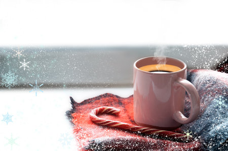 A mug of hot coffee is on the windowsill. Nearby lies a blue scarf and candy cane.の写真素材