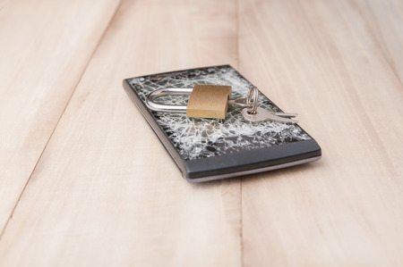 Key on smartphone broken screen on wood tableの写真素材
