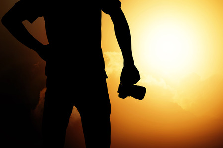 Man holding camera on sunset background , travel  , camera , success conceptの写真素材