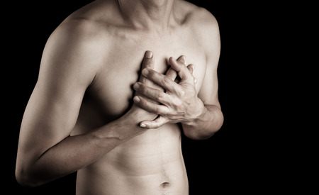 Hand of man adult touching chest with pain hurt ache on black background  people, healthcare body problem conceptの写真素材