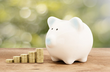 Piggy bank  and gold coin on wood floor with green bokeh background , saving banking ,family conceptの写真素材