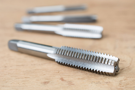 Screw tap cutting tool and broach on wood tableの写真素材