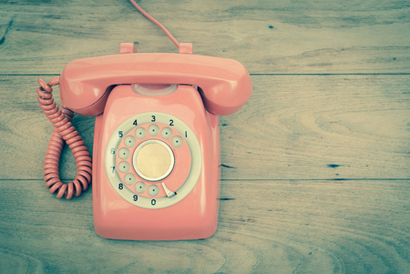Old phone rotary vintage retro stlye telephone on wood table top viewの写真素材