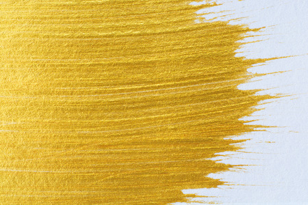 Gold acrylic paint on white paper background , gold texture free hand stoke object paintの写真素材