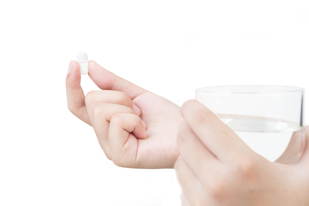 Hand of female holding paracetamol  pill  tablet medicine and glass of water on white backgroundの写真素材