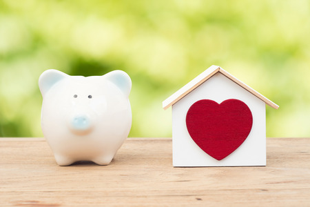 Piggy bank and house on wood floor with green bokeh background , save success business money financial planning conceptの写真素材