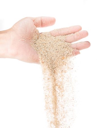 Hand pouring sand on white backgroundの写真素材