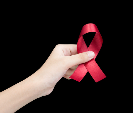 Hand holding red ribbon on black background sign of world aids day hiv , 1 december symbol of health cancer dayの写真素材