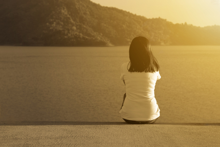 Women adult sit on the road alone with nature mountain and sunset backgroundの写真素材